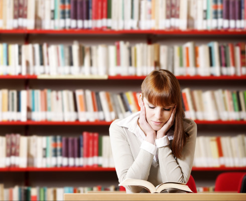Junge Frau liest in der Bibliothek
